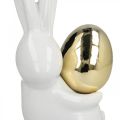 Floristik24 Lapins de Pâques élégants, lapins en céramique avec oeuf doré, décoration de Pâques blanc, doré H18cm 2pcs
